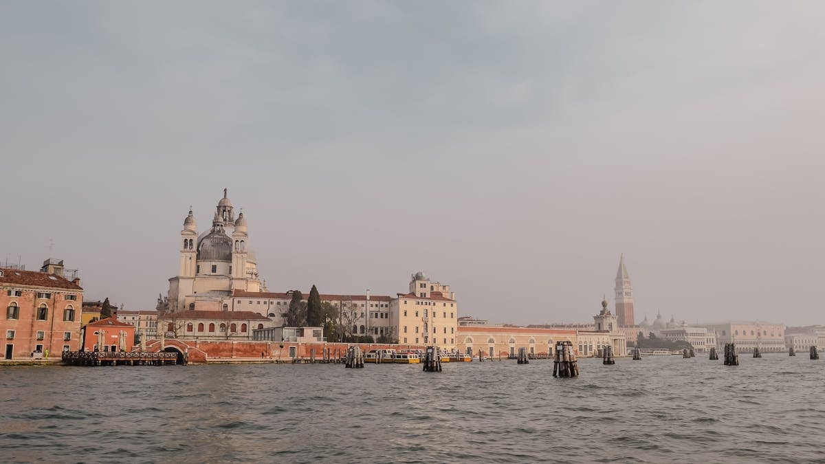 View of Santa Maria della Salute and Venice skyline from the water at sunset, featuring baroque architecture.